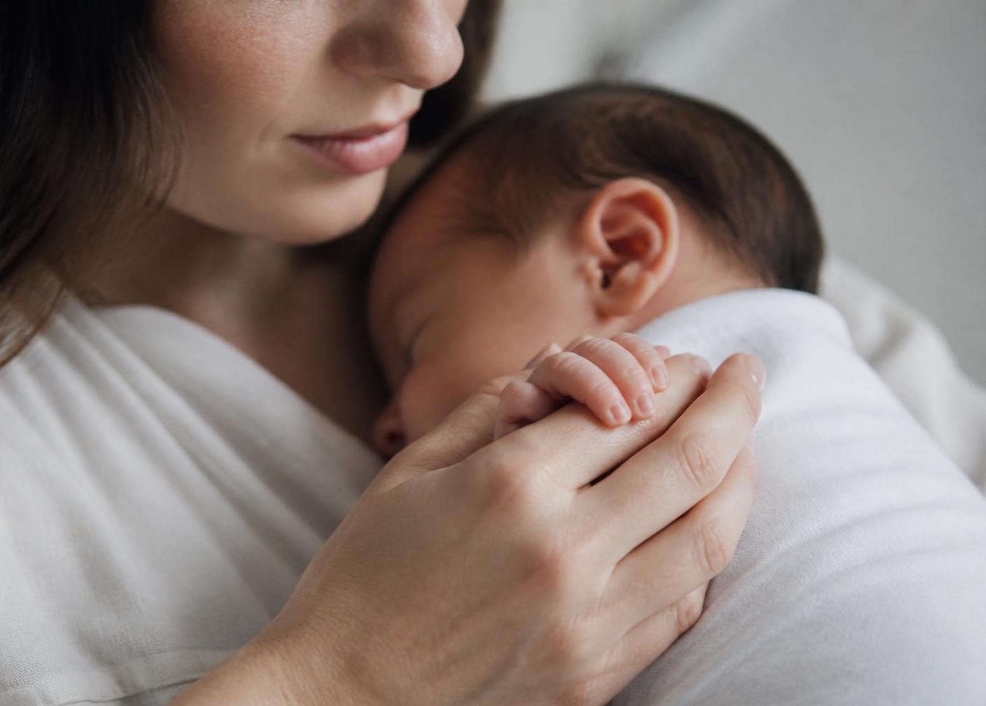 A mother holding her newborn's tiny hand